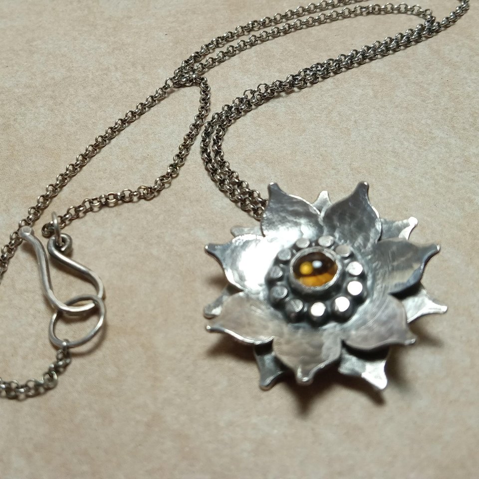 Argentium SS and citrine lotus flower pendant, showing clasp, Photo on sand color paper.
