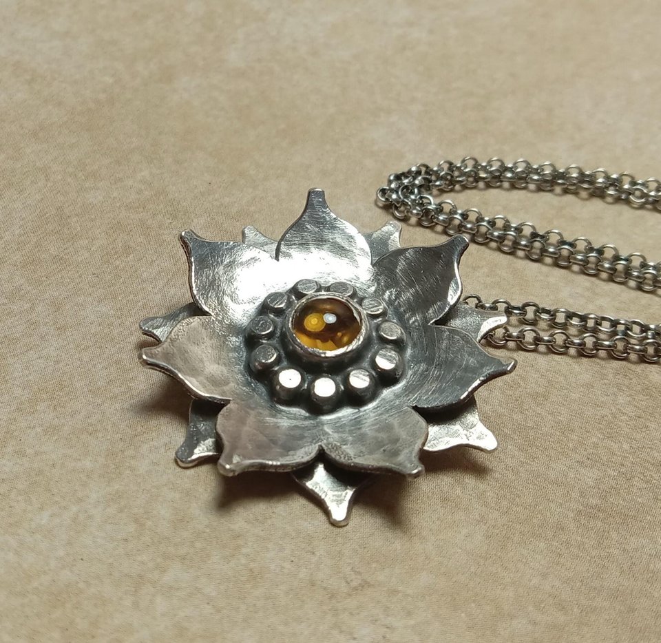 Lotus flower pendant with citrine, hammer textured argentium SS. Photo on sand color paper.