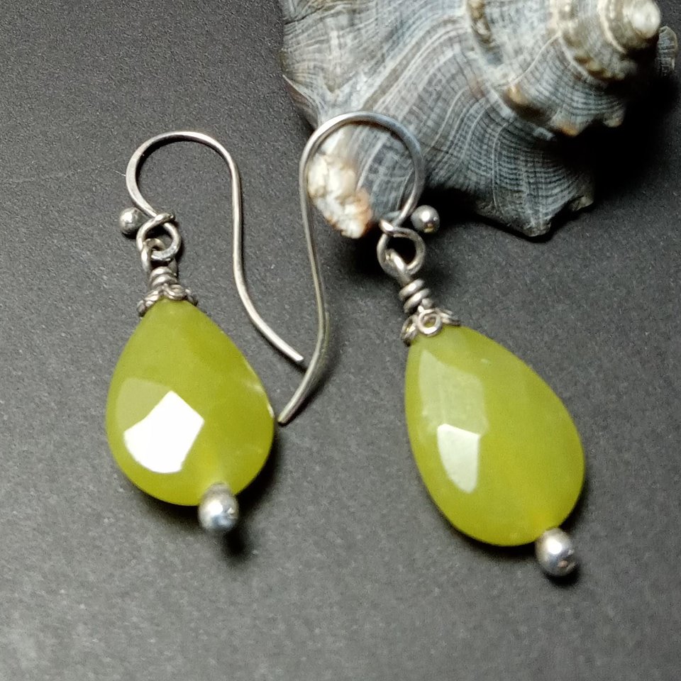 Faceted serpentine dangle earrings with sterling silver on shell and dark background.