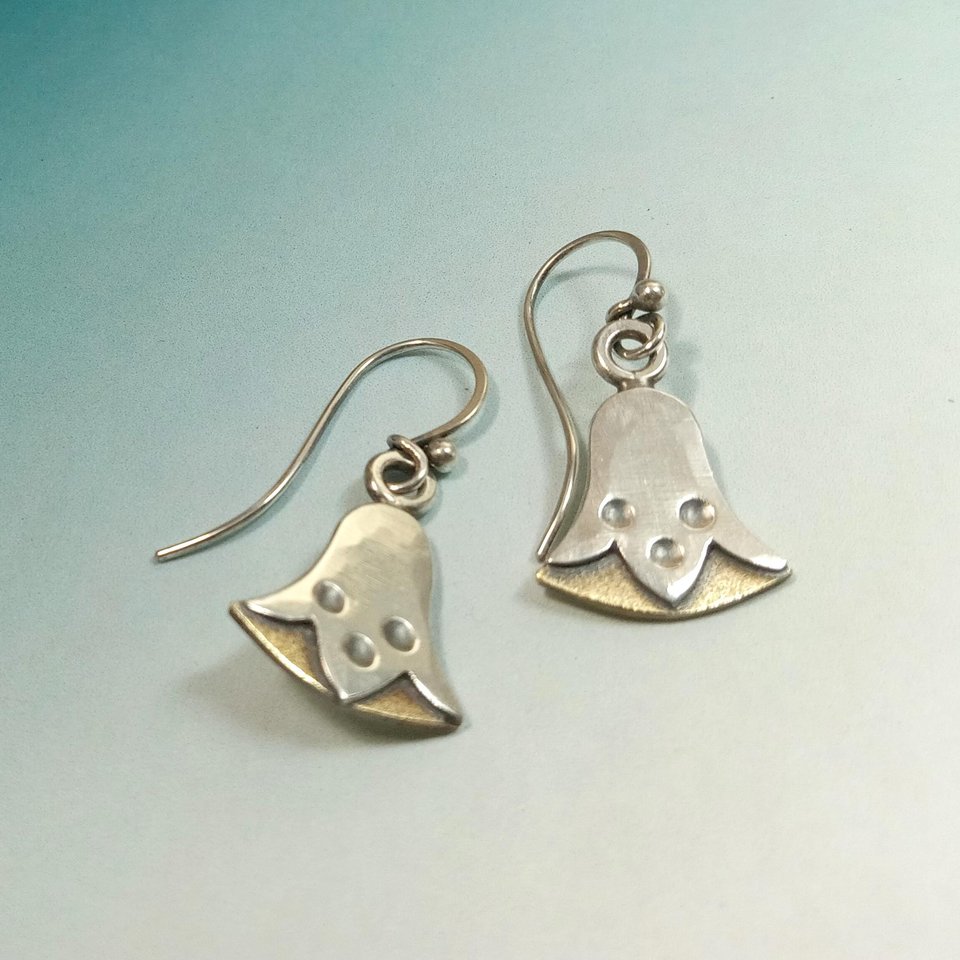 Bronze and silver egyptian lotus earrings by Mocahete on blue background.