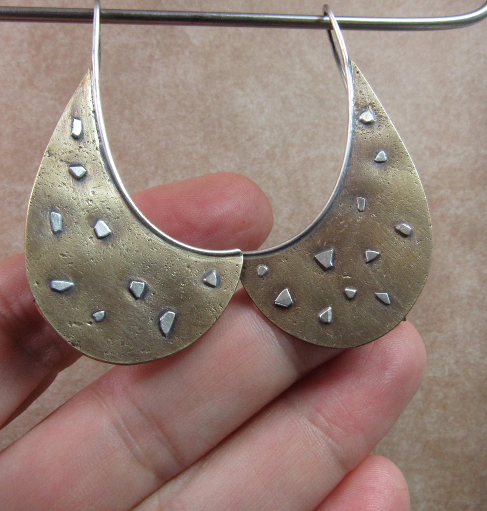 Unusual bronze and SS earrings photographed against hand.