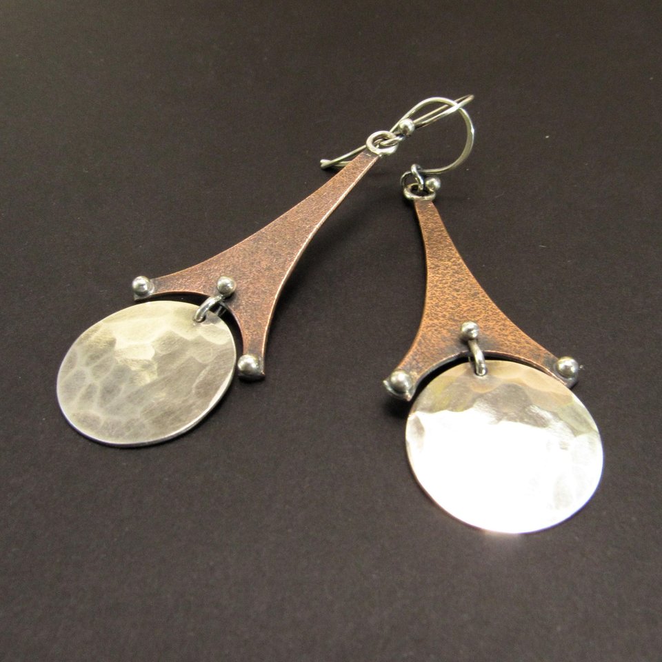 Long copper and silver earrings that resemble the Eiffel tower. 2.5" long, displayed on dark background.