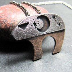 1. Mixed metal bear pendant with moon and stars inspired by Ursa Major photographed against rock.